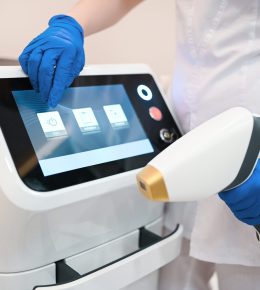 Apparatus for laser hair removal and the hands of a beautician cosmetologist in medical gloves. Epilation and spa concept