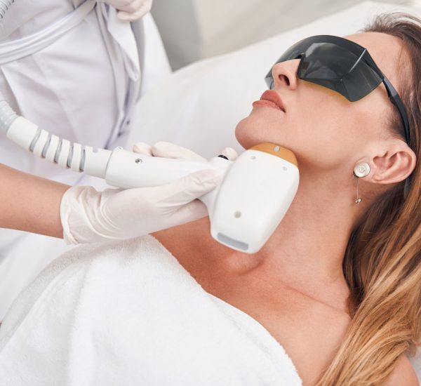 Calm female during laser treatment with professional Top view of tranquil young pretty woman visiting beauty salon for removing hair on face