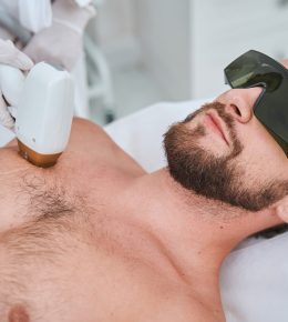 Beauty salon customer undergoing a laser chest hair removal Male client in safety goggles lying on the couch during a non-invasive medical procedure performed by a beautician