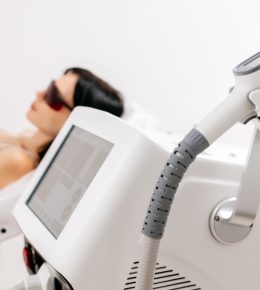 Body care concept. Laser hair removal. Young Caucasian woman in safety glasses lies on the sofa, female cosmetologist doing laser hair removal in a beauty salon Body care concept. Laser hair removal. Young Caucasian woman in safety glasses lies on the sofa, female cosmetologist doing laser hair removal in a beauty salon